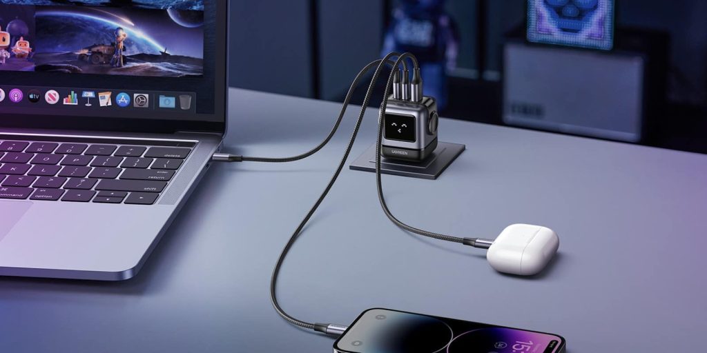 Un ordinateur portable, un iPhone et des écouteurs sans fil blancs sont connectés simultanément à un hub de charge multi-ports gris, mettant en évidence la capacité du chargeur rapide