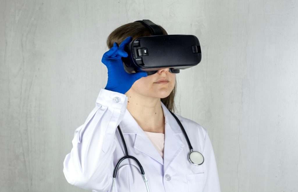 Médecin en blouse blanche et gants bleus utilisant un casque de réalité virtuelle, illustrant l'intégration de L'IA dans la Santé.