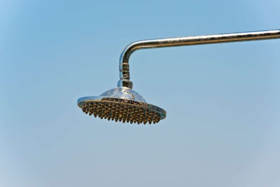 Un pommeau de douche chromé fixé à l'extérieur sous un ciel clair, idéal pour illustrer le choix d'un bon pommeau de douche.