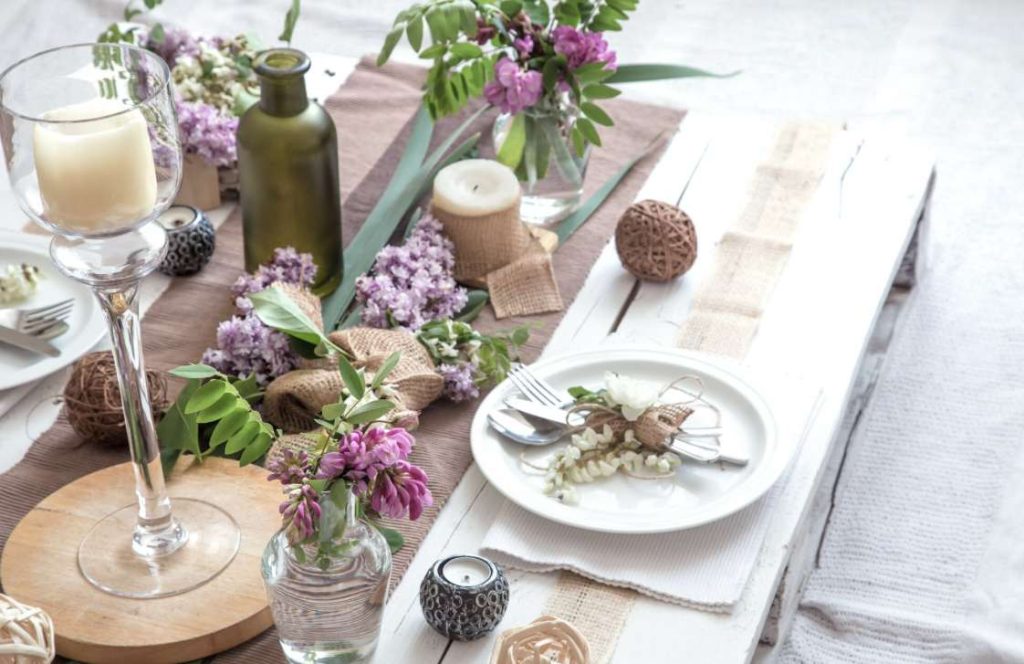 Table basse champêtre avec fleurs mauves et bougies montrant comment organiser un mariage intimiste petit budget avec du mobilier en palettes.